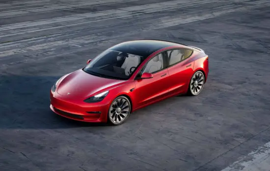Red Tesla Model 3 Long Range AWD (2021+) electric sedan parked on an open surface, featured by DRIVEN Newmarket.