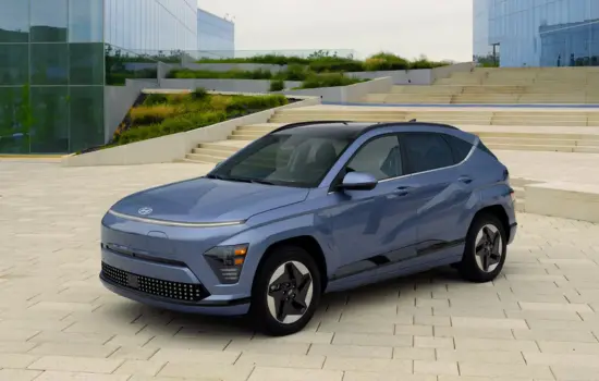 Blue Hyundai Kona Electric (2019–2023) electric SUV parked in a modern urban setting, featured by DRIVEN Newmarket.