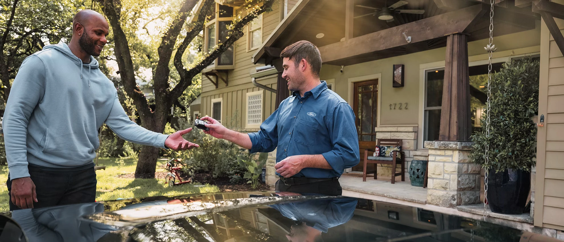 Ford employee handing unknown person a key as they stand outside a house