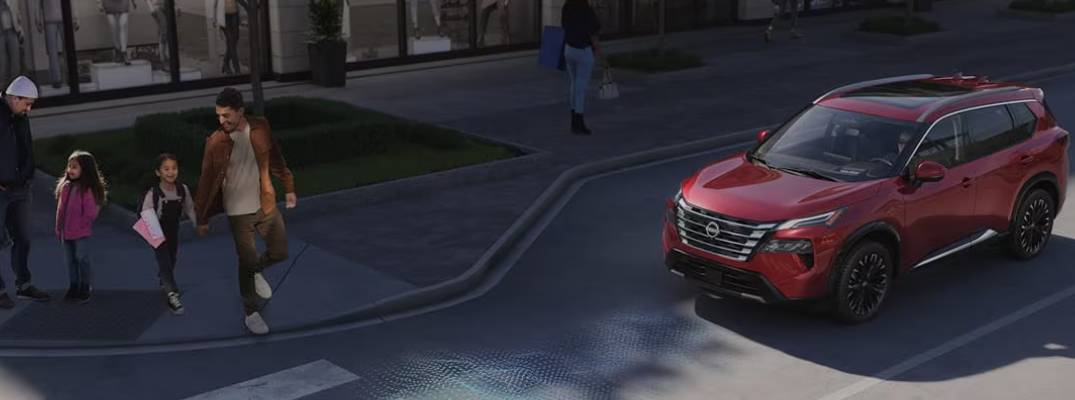 2026 Nissan Rogue on road with people walking nearby