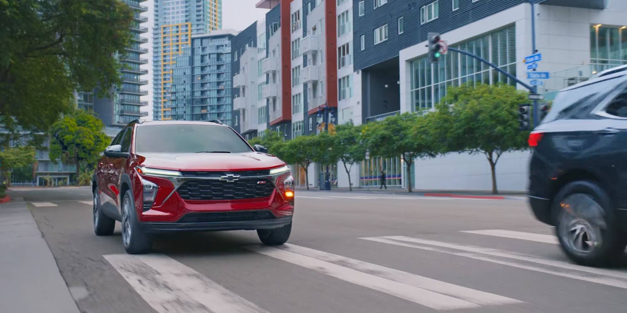 A red 2026 Chevrolet Trax drives through a city