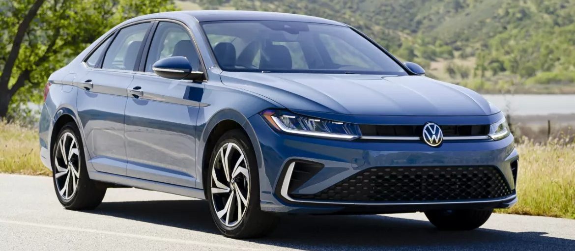 Front side view of Jetta parked with greenery in background