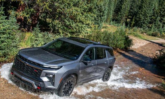 grey_2026_chevrolet_traverse_driving_on_river_stream_near_forest.jpg
