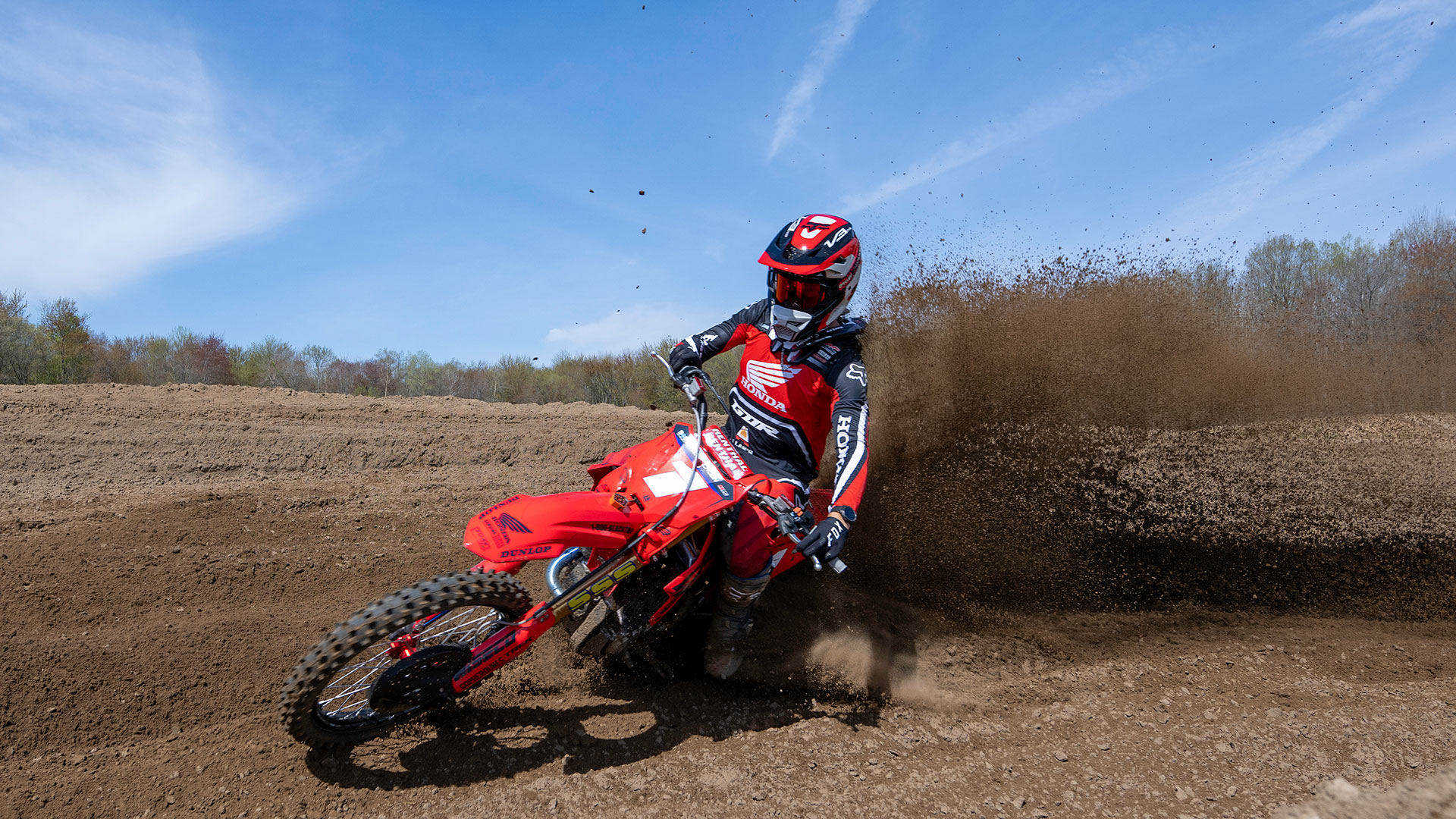 Rider on a Honda CRF450R making a turn and kicking up dirt