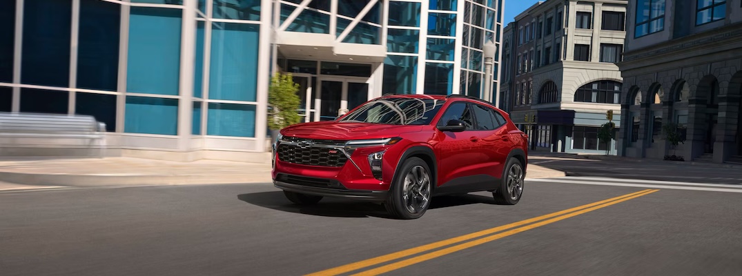 A red 2026 Chevrolet Trax drives through town.