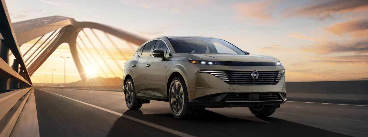A silver 2025 Nissan Murano drives in front of a dramatic sunset