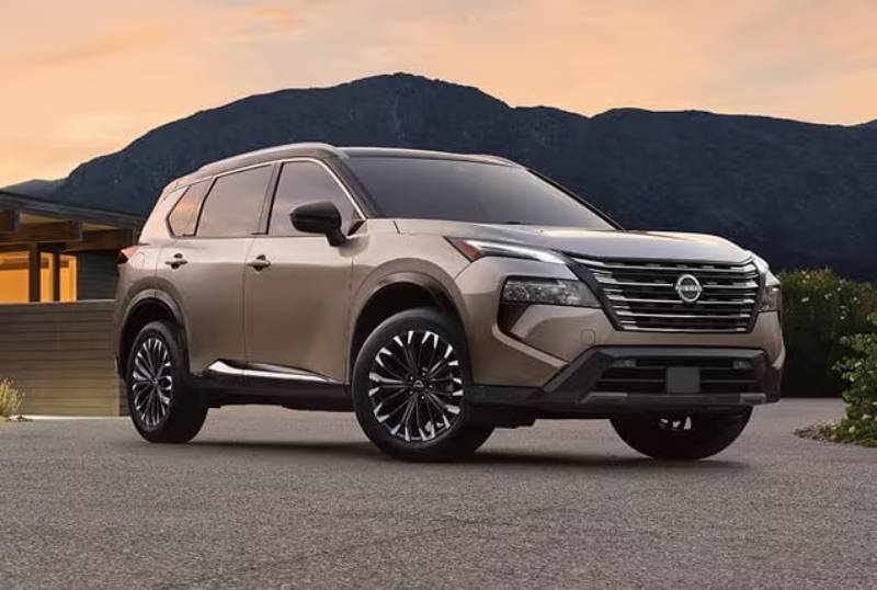 A brown 2026 Nissan Rogue is parked in front of a mountain as the sun sets