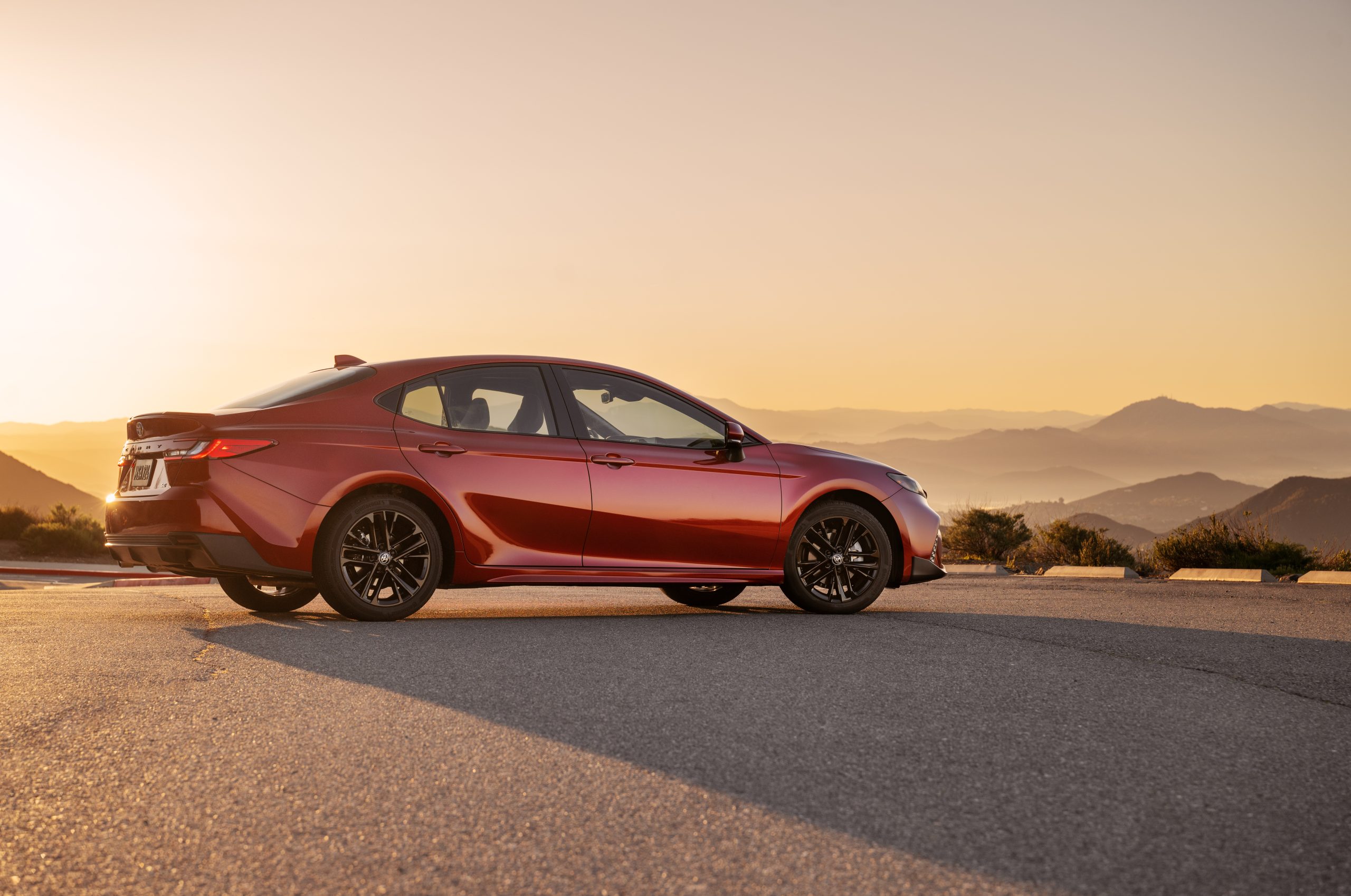 2026 Toyota Camry in Supersonic Red Nightshade Edition parked at sunset with mountain views in the background.