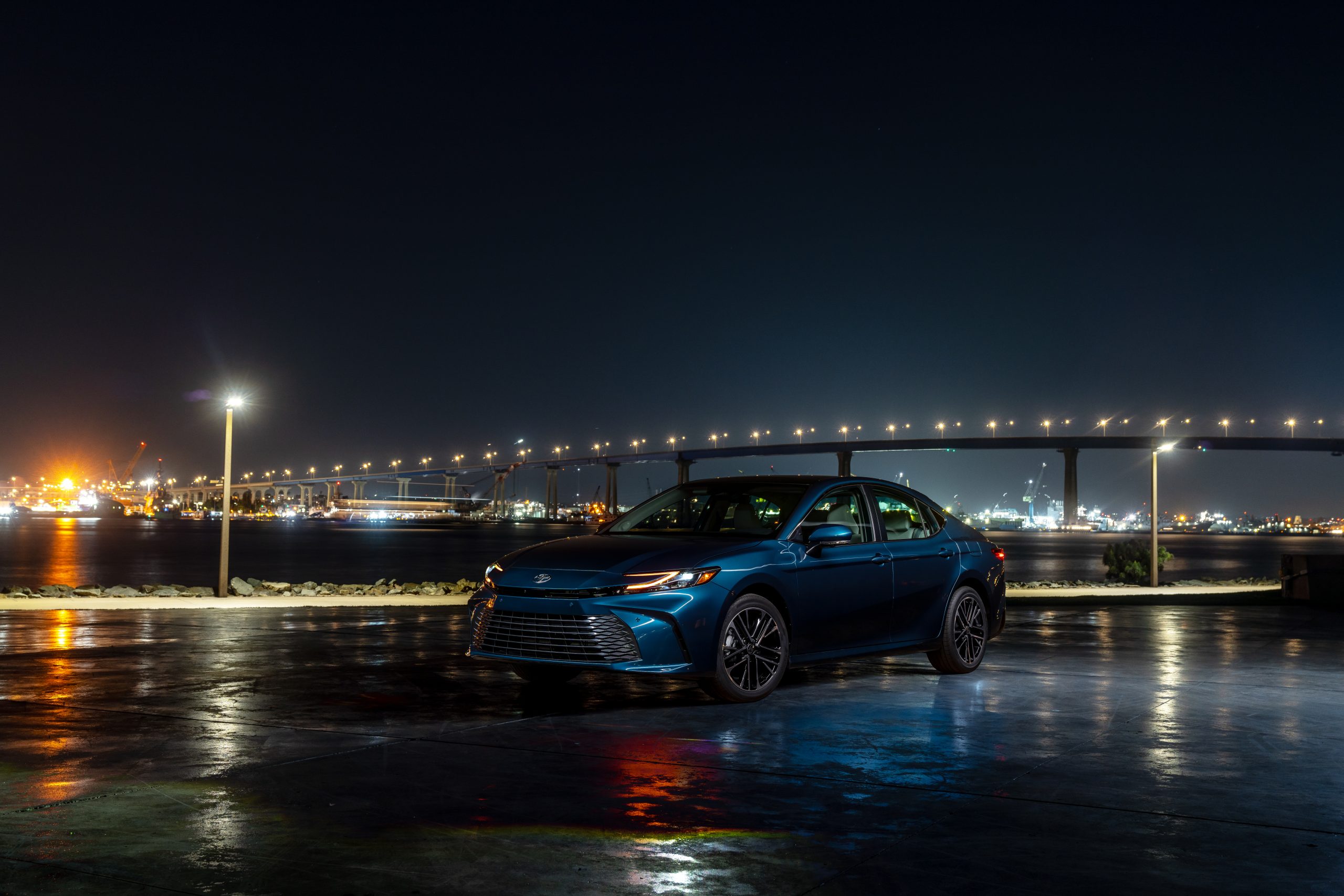 2026 Toyota Camry XLE in Ocean Gem parked by a waterfront bridge at night.