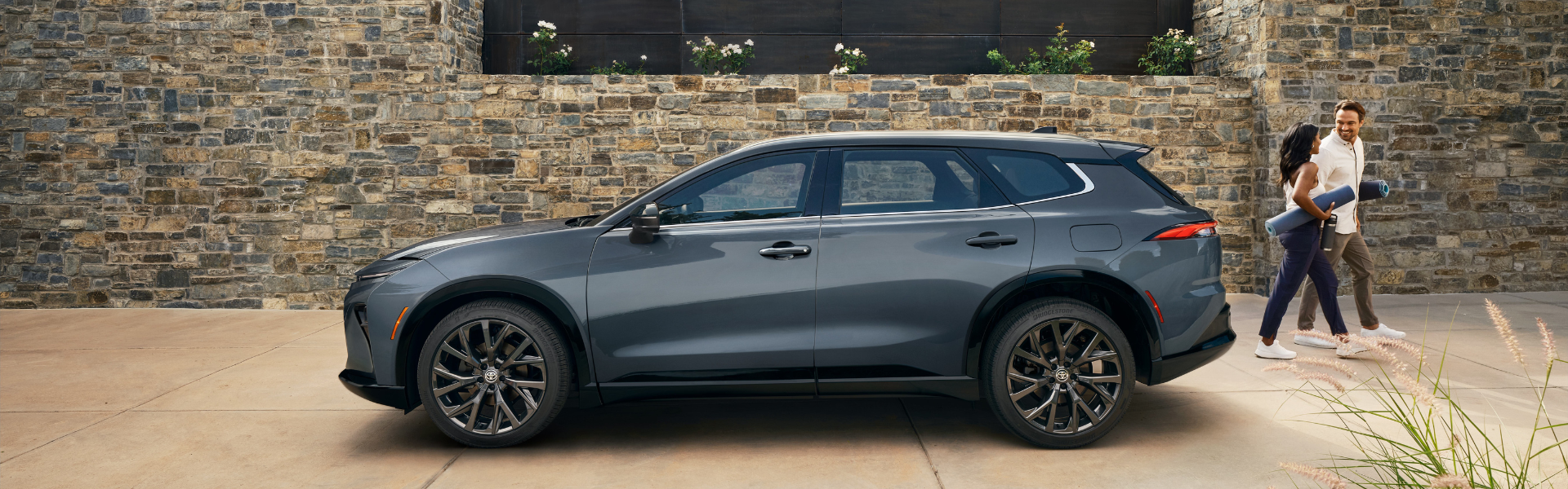 Side view of a Toyota Crown Signia parked outdoors with two people walking nearby