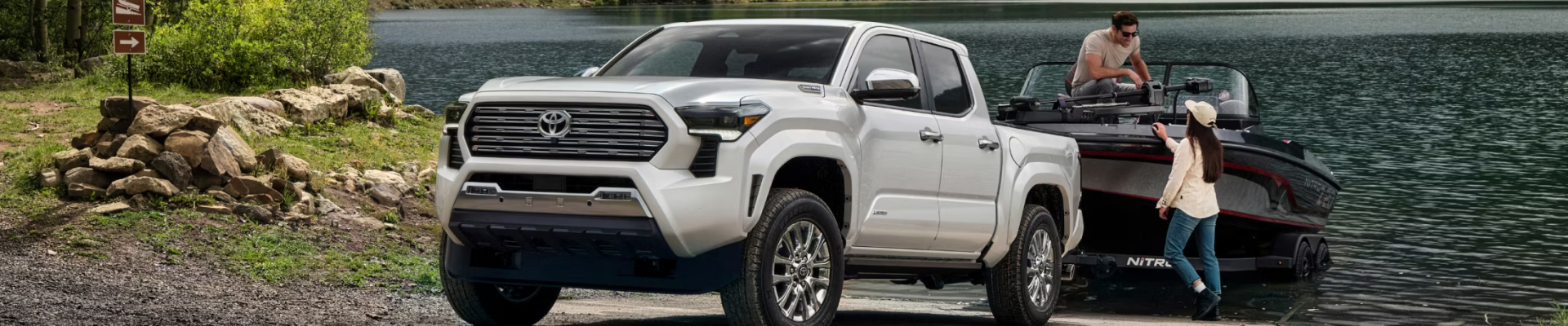 Toyota Tacoma parked near water with a boat trailer attached