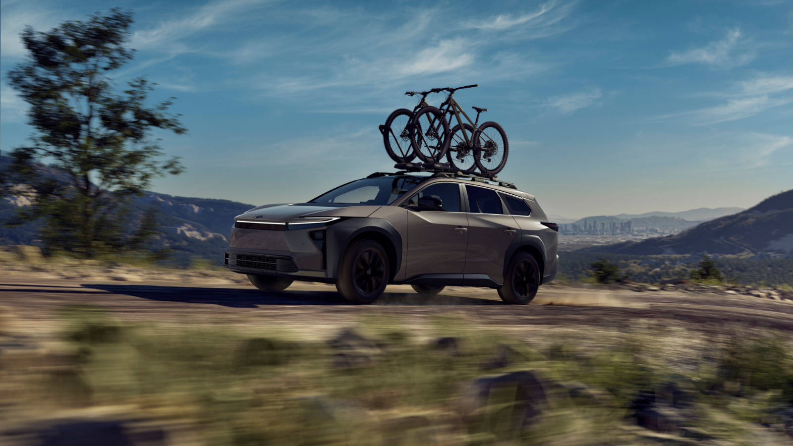 2026 Toyota bZ Woodland driving on a rugged trail with bicycles mounted on the roof