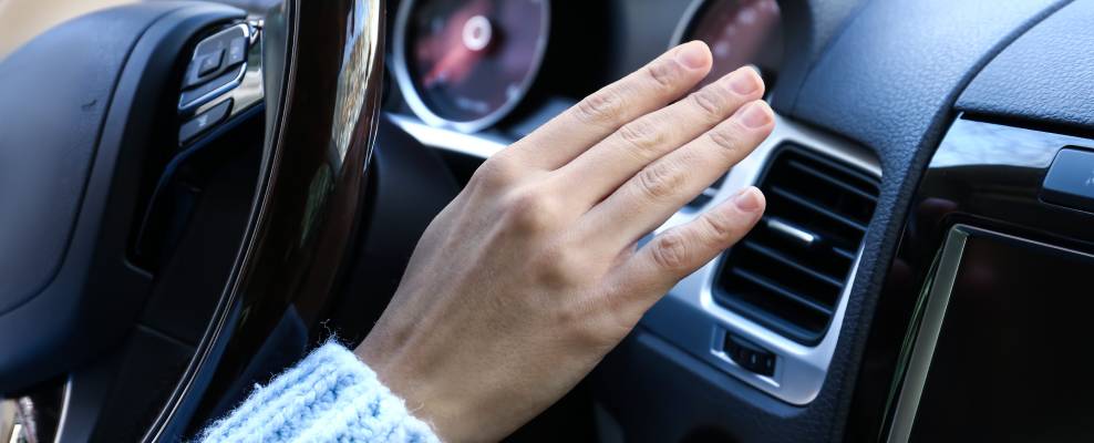 A hand hovers over a car heater vent
