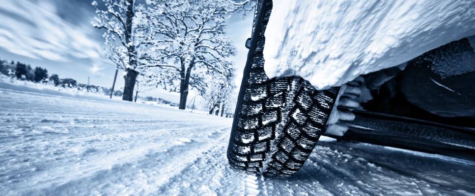 A close up of a vehicle's winter tires as it drives over snow