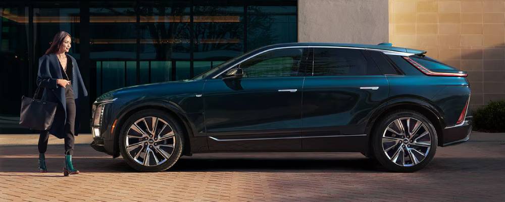 A woman walks towards a green 2026 Cadillac LYRIQ. 2026 Cadillac LYRIQ performance specs at FFUN Cadillac
