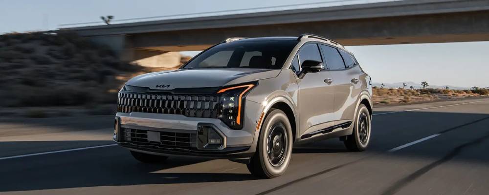 A brown 2026 Kia Sportage drives under an underpass on the highway. New 2026 Kia Sportage for sale at FFUN Yorkton Kia