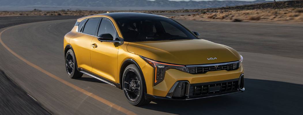 A yellow 2026 Kia K4 Hatchback drives past the camera at an angle