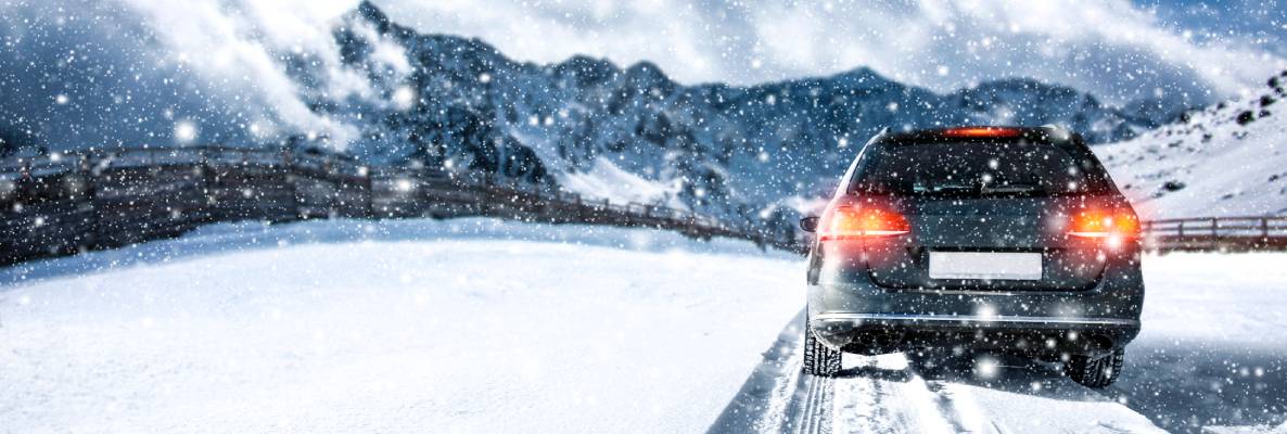 An SUV drives across a snowy white field with its taillights on.