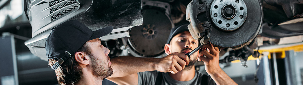 professional mechanics repairing car without wheel in auto repair shop
