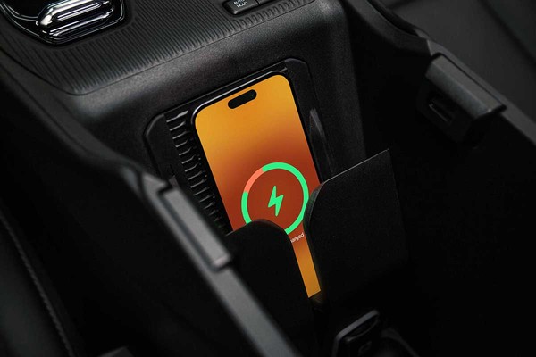 A smartphone with a orange screen charges in the 2026 Jeep Cherokee's wireless charging pad