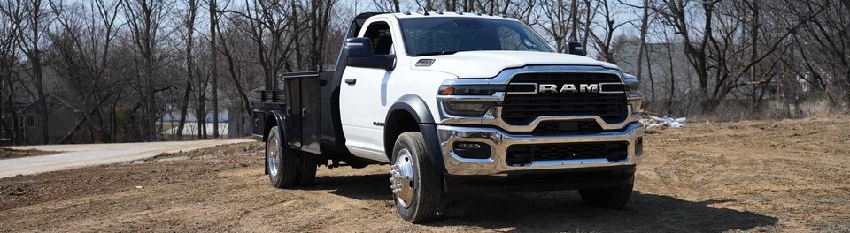 A white 2026 Ram Chassis Cab is parked on grass in front of a line of winter trees. New 2026 Ram Chassis Cab for sale at Laplante Chrysler Dodge Jeep Ram in Embrun, ON