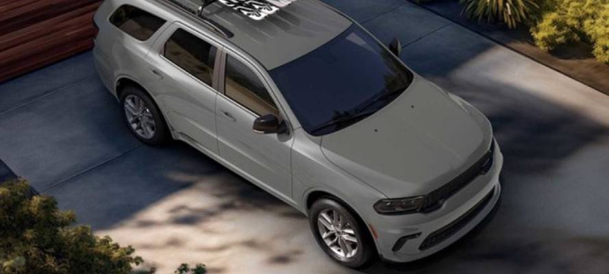 A silver 2026 Dodge Durango is parked in front of a home. It has a roof rack equipped.