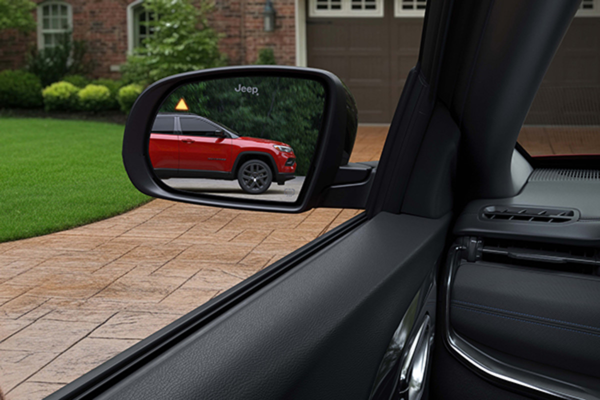 A 2026 Jeep Compass detects a red vehicle in its left side mirror