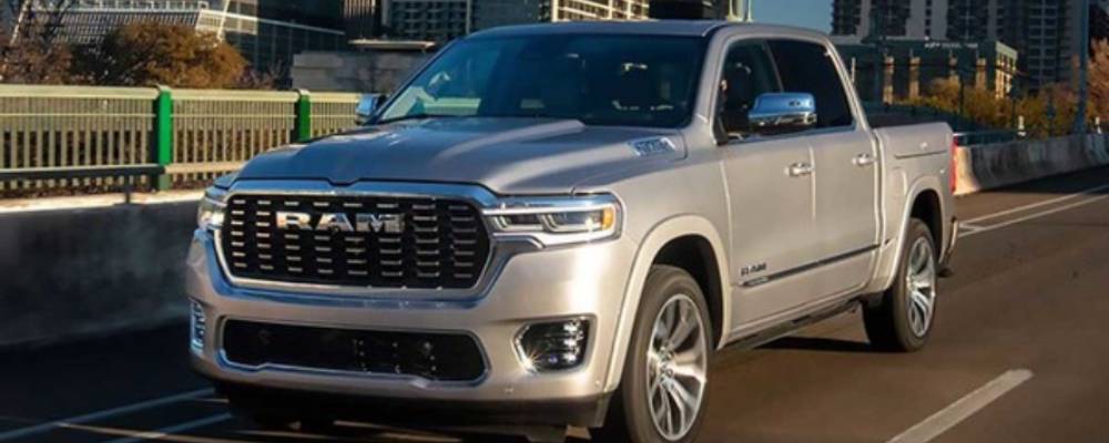 A silver 2026 Ram 1500 drives through a city