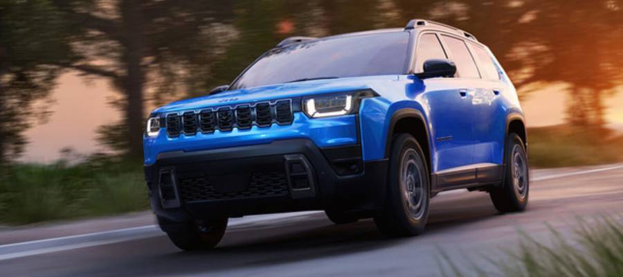 A blue 2026 Jeep Cherokee travels towards the camera at an angle