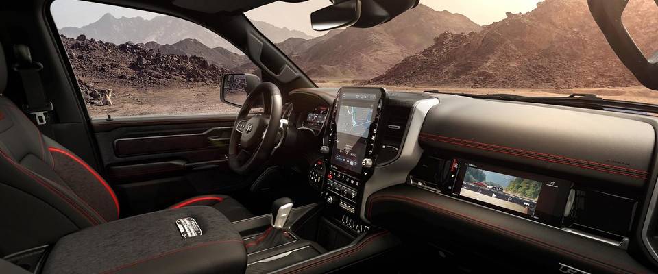 The interior front seat of a 2026 Ram 1500 with black seats and red accents. The shot captures the digital rearview mirror and infotainment screens.