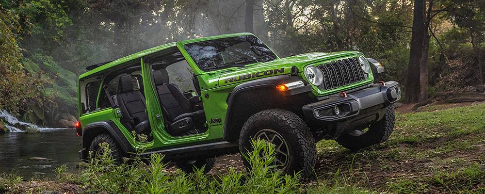 A doorless 2026 Jeep Wrangler in Mojito! is parked in a forest. 2026 Jeep Wrangler performance specs at Leavens Chrysler Dodge Jeep Ram in London, ON