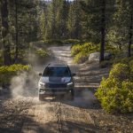 2026 Jeep Compass Trailhawk SUV driving on a dusty dirt road through a pine forest, front view used by Leavens Chrysler Dodge Jeep RAM London Ontario.