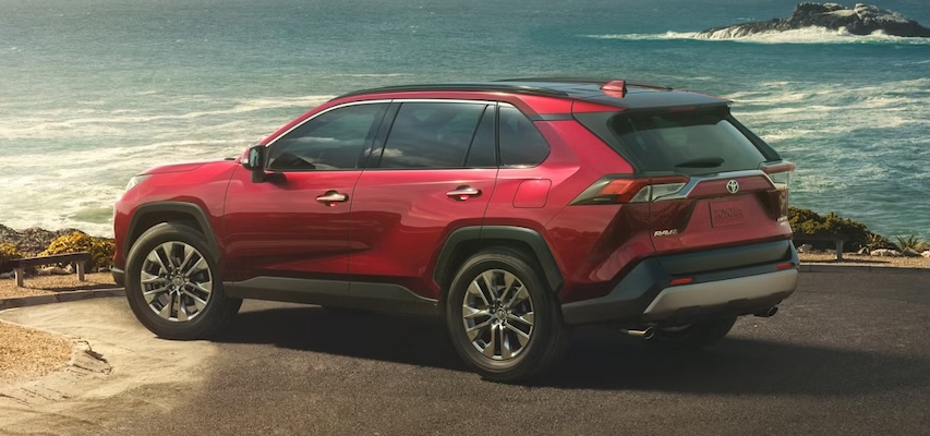 A red 2025 Toyota RAV4 sits near a beach.