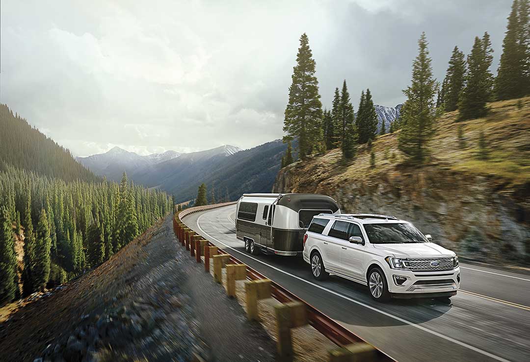 vue trois quart avant du Ford Expedition 2021 roulant avec une roulotte sur une route