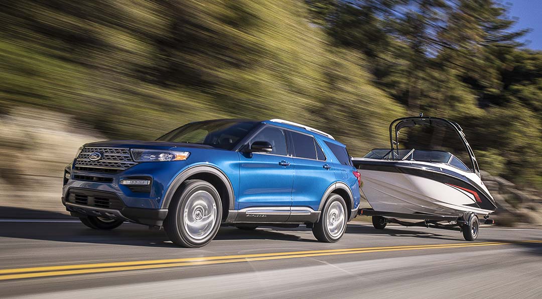 vue latérale du Ford Explorer 2019 sur une route avec une batteau en remorque