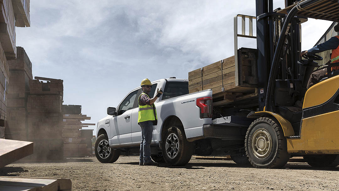 vue trois quart arrière du Ford F-150 Lightning 2022 avec un chargement de bois