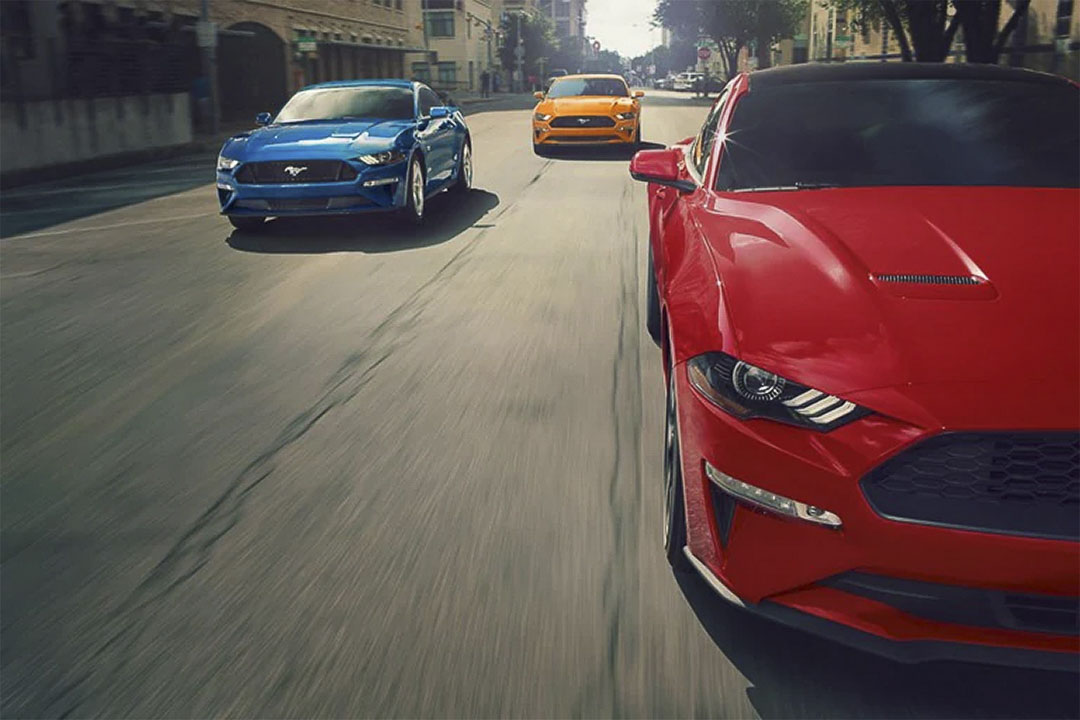 vue avant de trois Ford Mustang Mach 1 sur une rue