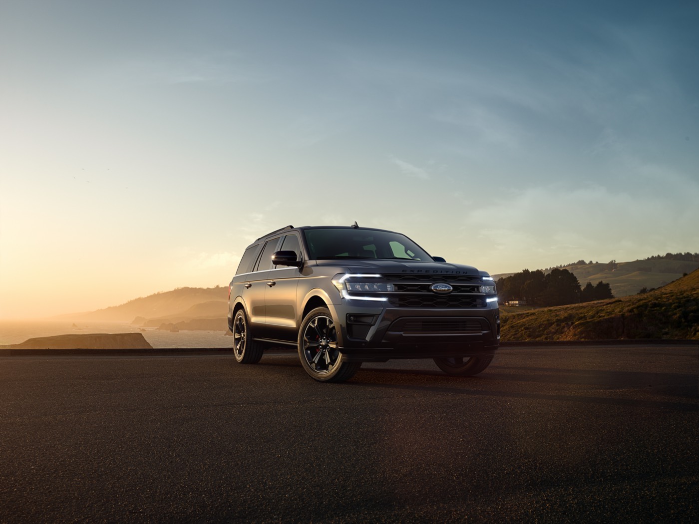 Vue 3/4 avant d'un VUS Ford Expedition 2022 avec ses phares allumés garé sur plateforme dos à la mer