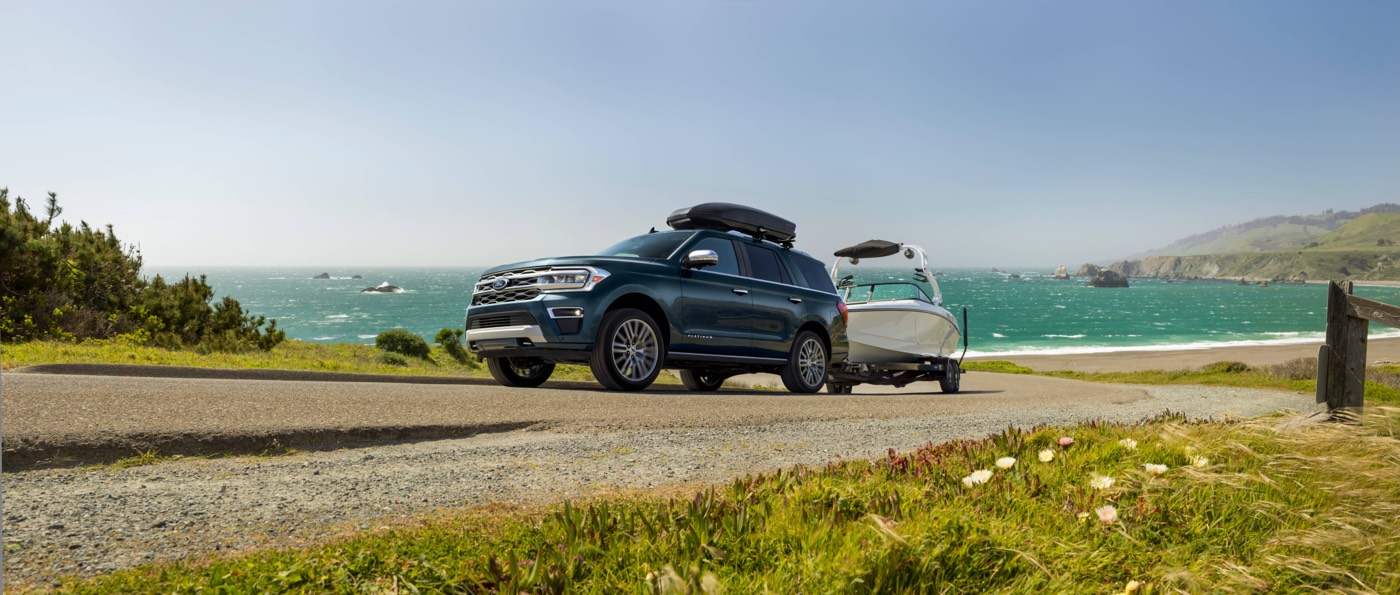 Un VUS Ford Expedition Platinum 2022 remorquant un bateau sur une route non loin d'une plage