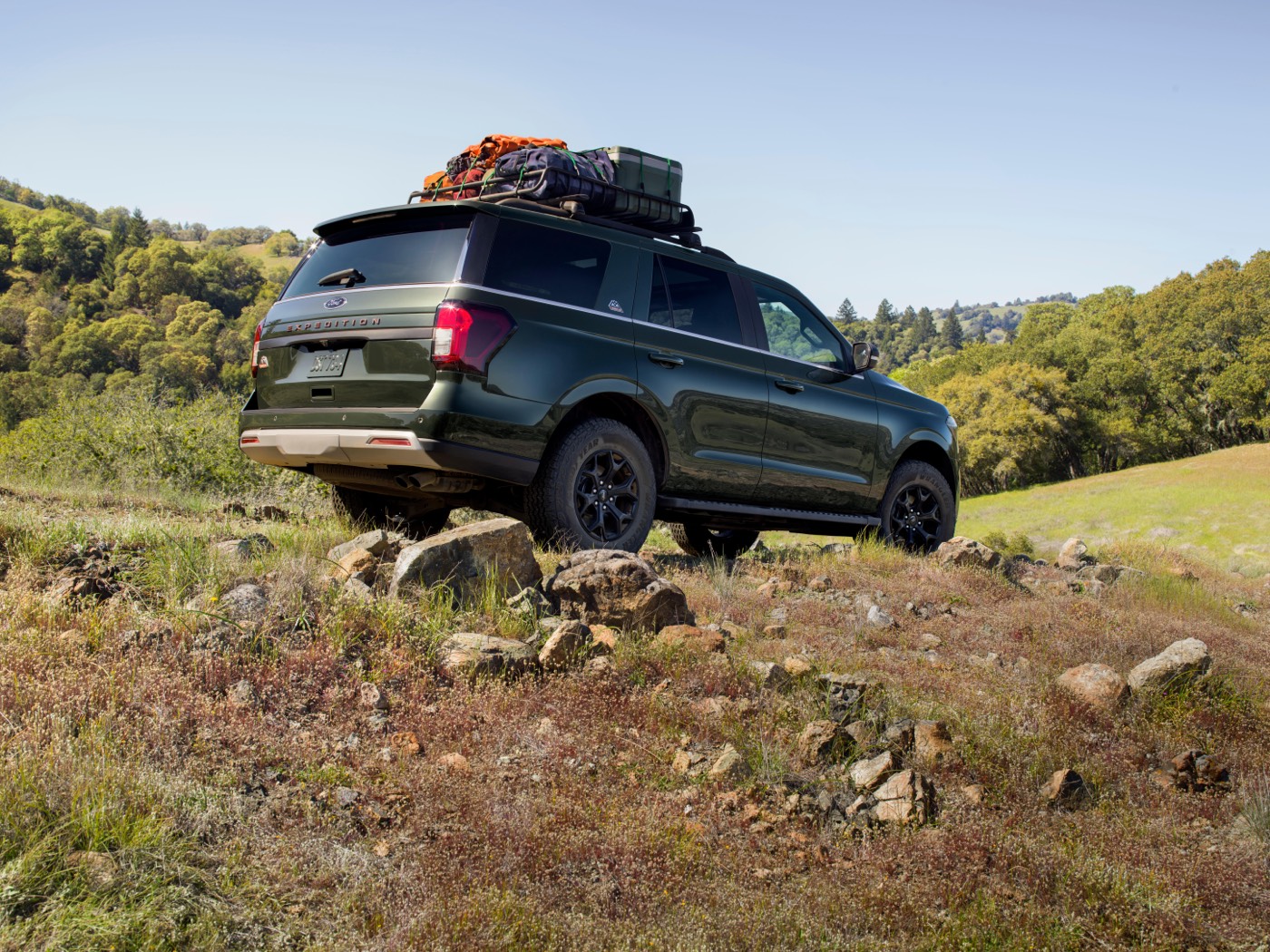 Vue 3/4 latérale et arrière du Ford Expedition Timberline 2022 garé en nature avec des bagages attachés sur le toit du VUS