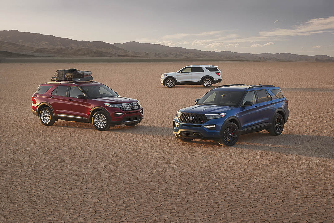 Trois VUS Ford Explorer ST rouge 2022, bleu et blanc garés sur une terre désertique avec des montagnes au loin