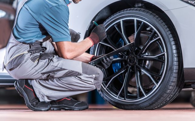 A mechanic checks over the tire of a car.