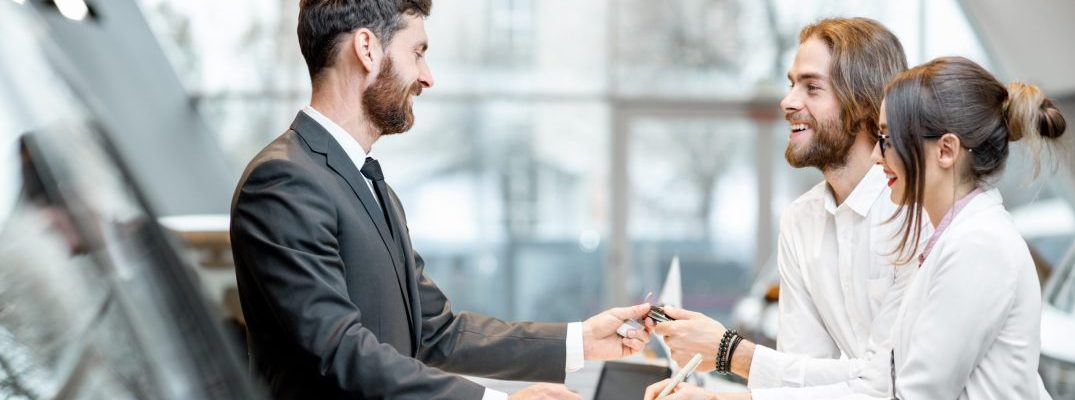 A couple gets keys to a car from a salesman.