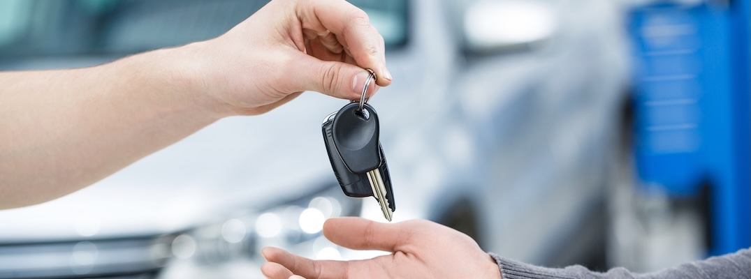 A salesman hands over the keys to a car.