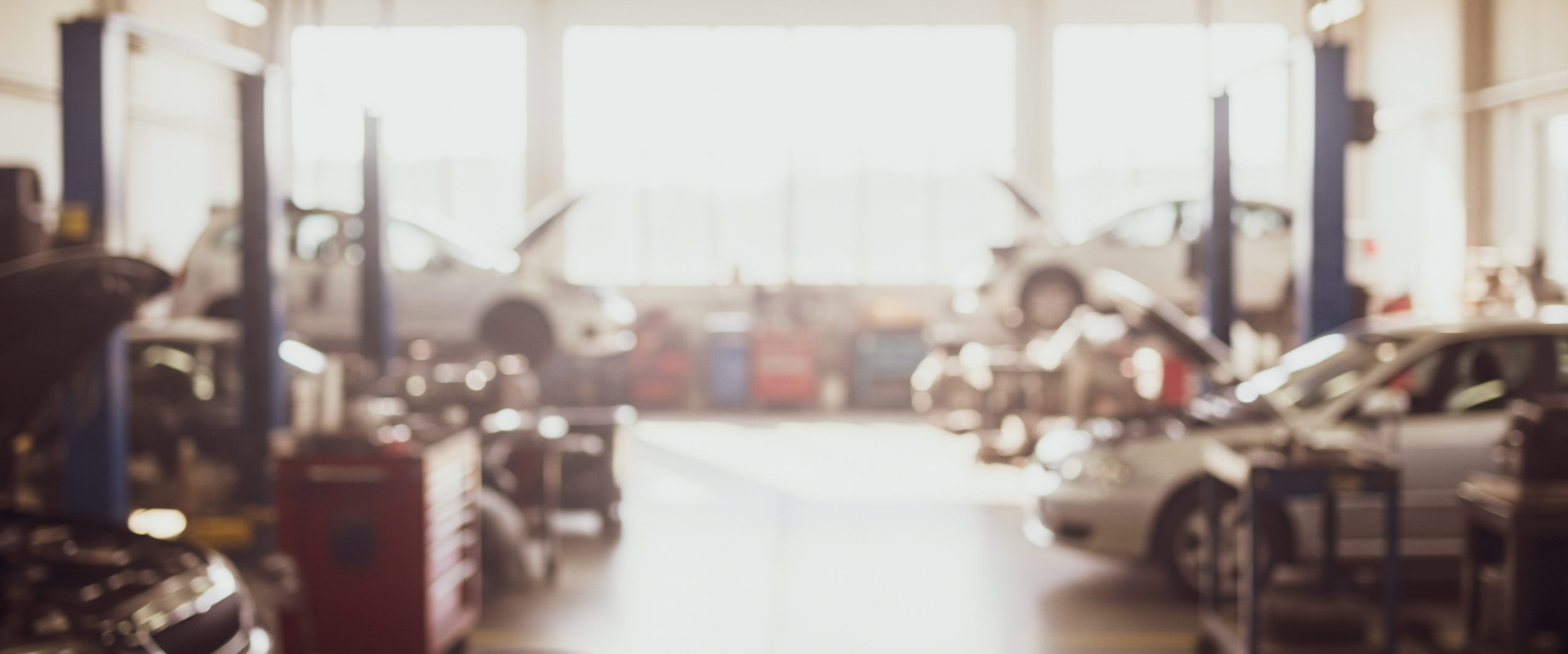 Cars are being repaired in a garage with lifts and tools.