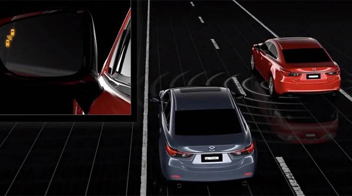 An image representing ActivSense's Blind Spot Monitoing System. One car passes another, and a small cutaway window shows off the car in front detecting the passing one.