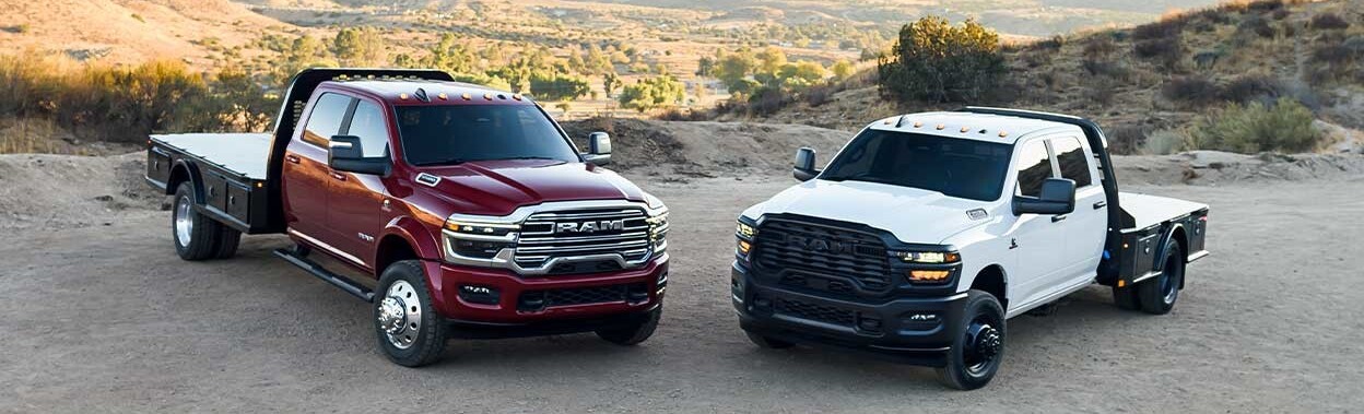 Two 2025 Ram 5500 Chassis Cabs parked on dirt road during daytime.