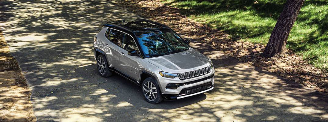 2025 Jeep Compass driving on shaded street.