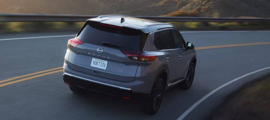 A silver 2026 Nissan Rogue drives down a highway showing off its LED taillights