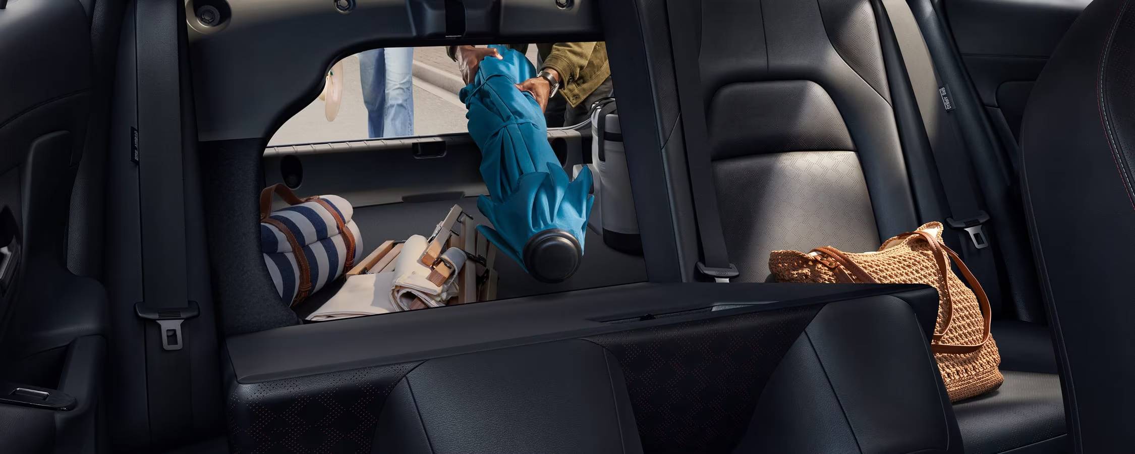A person loads a folded blue umbrella into the trunk of a 2026 Nissan Sentra. 2026 Nissan Sentra vs 2026 Hyundai Elantra at Medicine Hat Nissan in Medicine Hat, AB